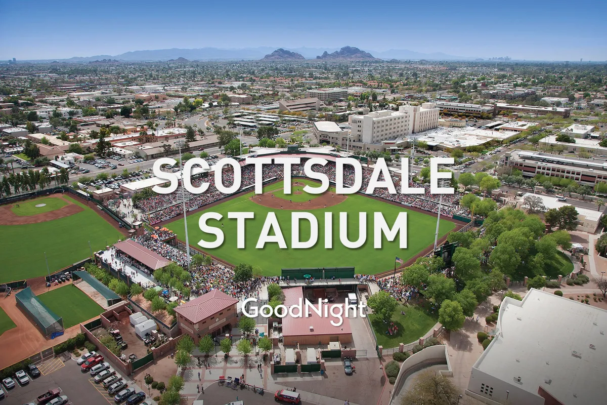 The lively atmosphere of Salt River Fields with its baseball field, a crowd of spectators in the stands, and surrounding mountains. The image captures the excitement of a group outing to a sporting event, perfect for team bonding.