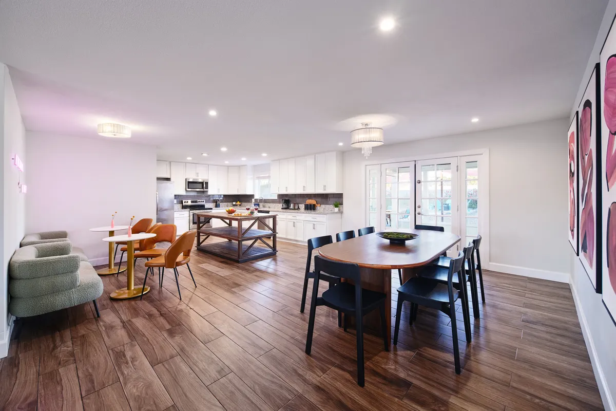 A warm, open dining area and kitchen blend seamlessly together, featuring a dining table, kitchen island, stylish artwork, and cozy seating. The layout is inviting for both family meals and entertaining guests, and the decor adds a unique, welcoming touch.